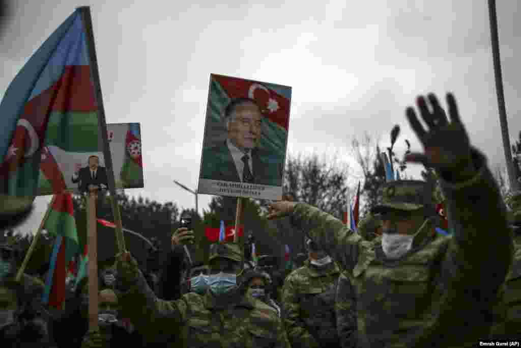 Azerbaijani soldiers hold national flags and portraits of Azerbaijani President Ilham Aliyev, left, and his father, the late President Heydar Aliyev, as they celebrate the return of the Lachin district to Azerbaijan's control on December 1, 2020. The region, which neighbors breakaway Nagorno-Karabakh, had been under Armenian control since May 1992.&nbsp;