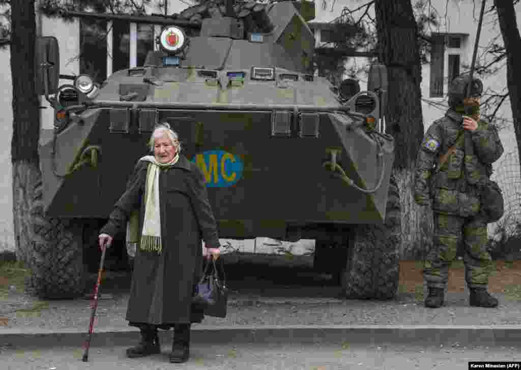 Five days before the arrival of Azerbaijani troops on December 1, 2020, Margarita Khanaghian, 81, walks past an armored personnel carrier for Russian peacekeepers in the town of Lachin (Berdzor). How many of the town's ethnic Armenian residents opted to stay despite the town's return to Azerbaijani control is unknown.&nbsp;