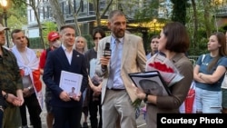 Светлана и Сергей Тихановские во время встречи с представителями белорусской диаспоры в Нью-Йорке. Слева – Евгений Жданович с папкой с именем Артура Сенько