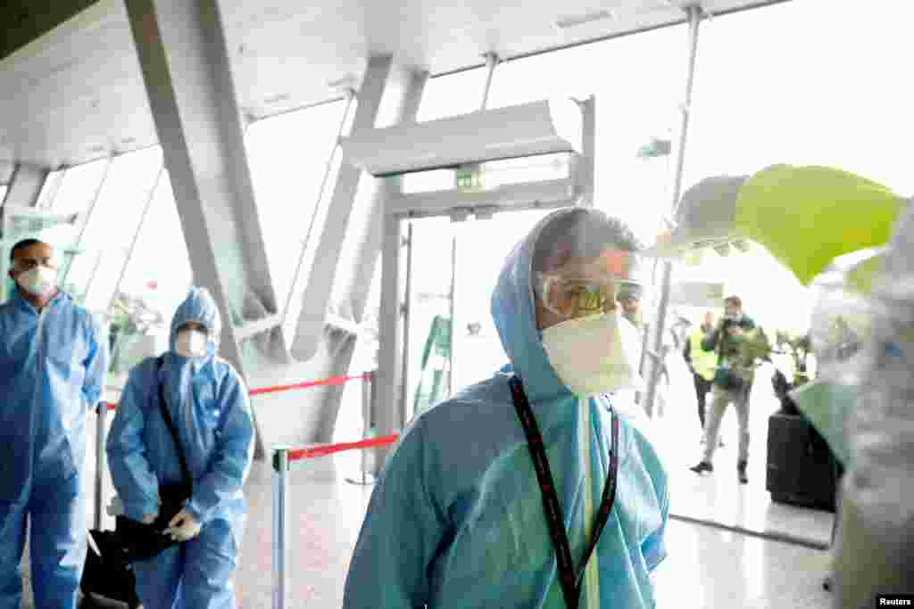 Сотрудники "Албанских авиалиний" в защитных костюмах проверяют температуру по прилету в Тирану, Албания.&nbsp;1 апреля 2020 года