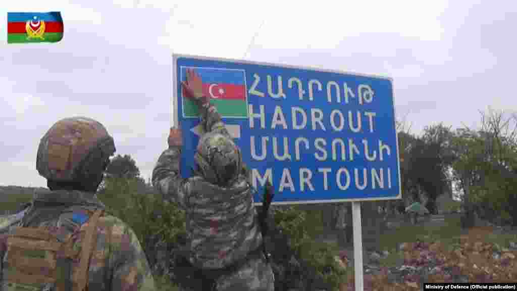 In this photo from the Azerbaijani Defense Ministry, Azerbaijani soldiers place an Azerbaijani flag on a sign for a road leading to the Karabakhi towns of Hadrut and Martuni (Khojavend). The photo was taken in Azerbaijan's southwestern Jabrayil region, one of seven territories surrounding Nagorno-Karabakh that have been occupied by Armenian forces since the two countries' 1992-1994 war.&nbsp;&nbsp;