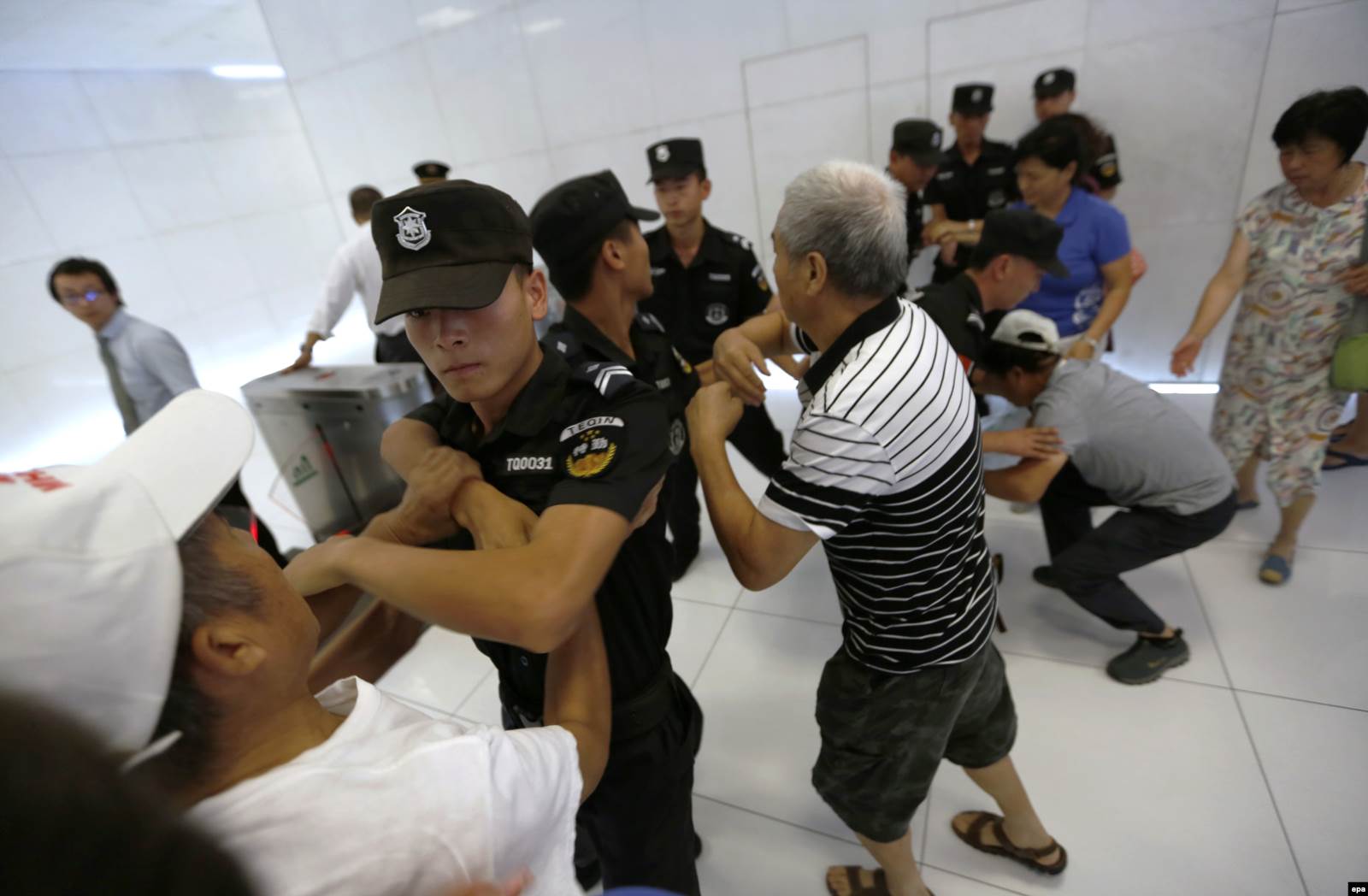 Родственники китайских пассажиров MH370 пытаются прорваться в офис Malaysia Airlines в Пекине, 5 августа 2015 года. Фото: EPA