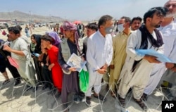 A man holds a certificate acknowledging his work for Americans as hundreds of people gather outside the international airport in Kabul on August 17, 2021.
